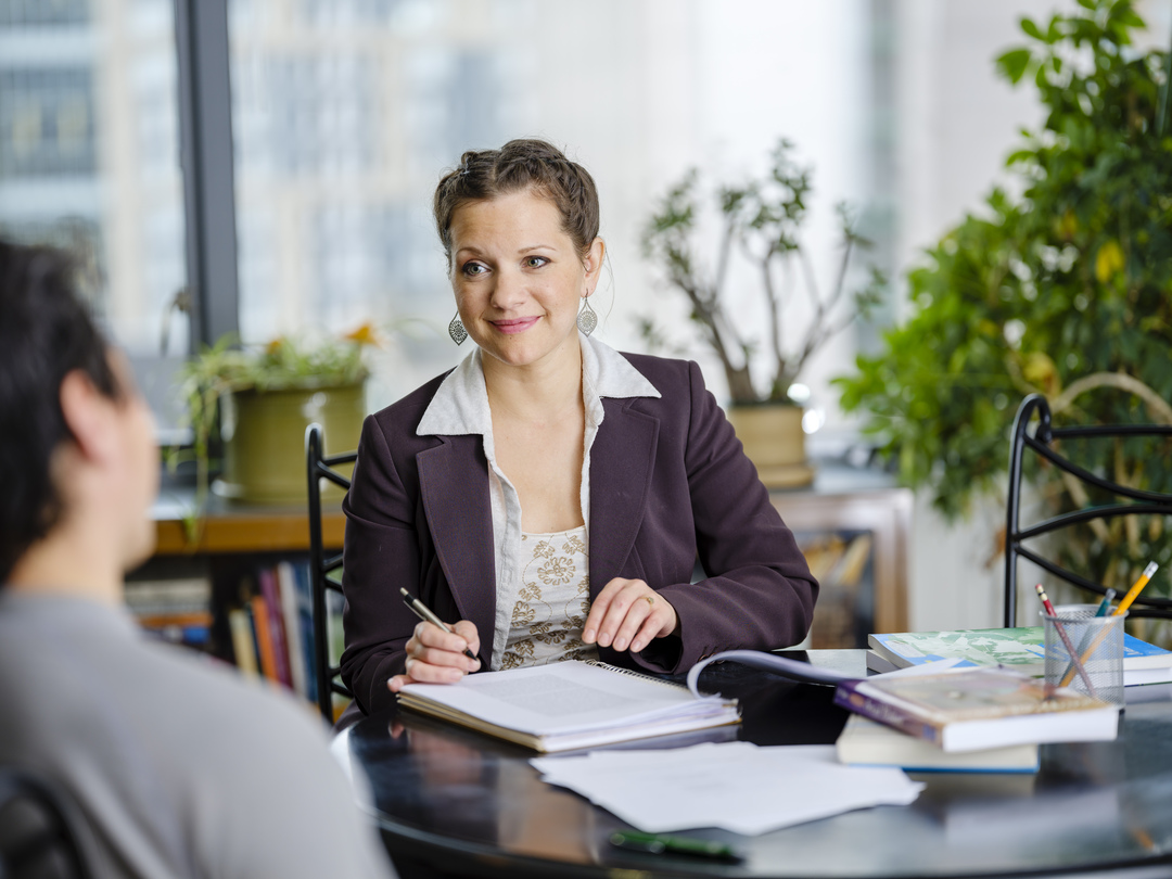 Woman behind desk smiling at student